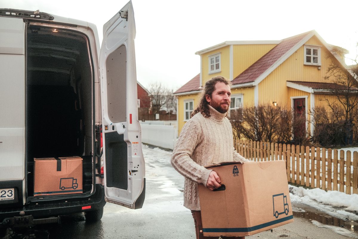 Maður ber kassa úr sendibíl frá Hertz í flutningum
