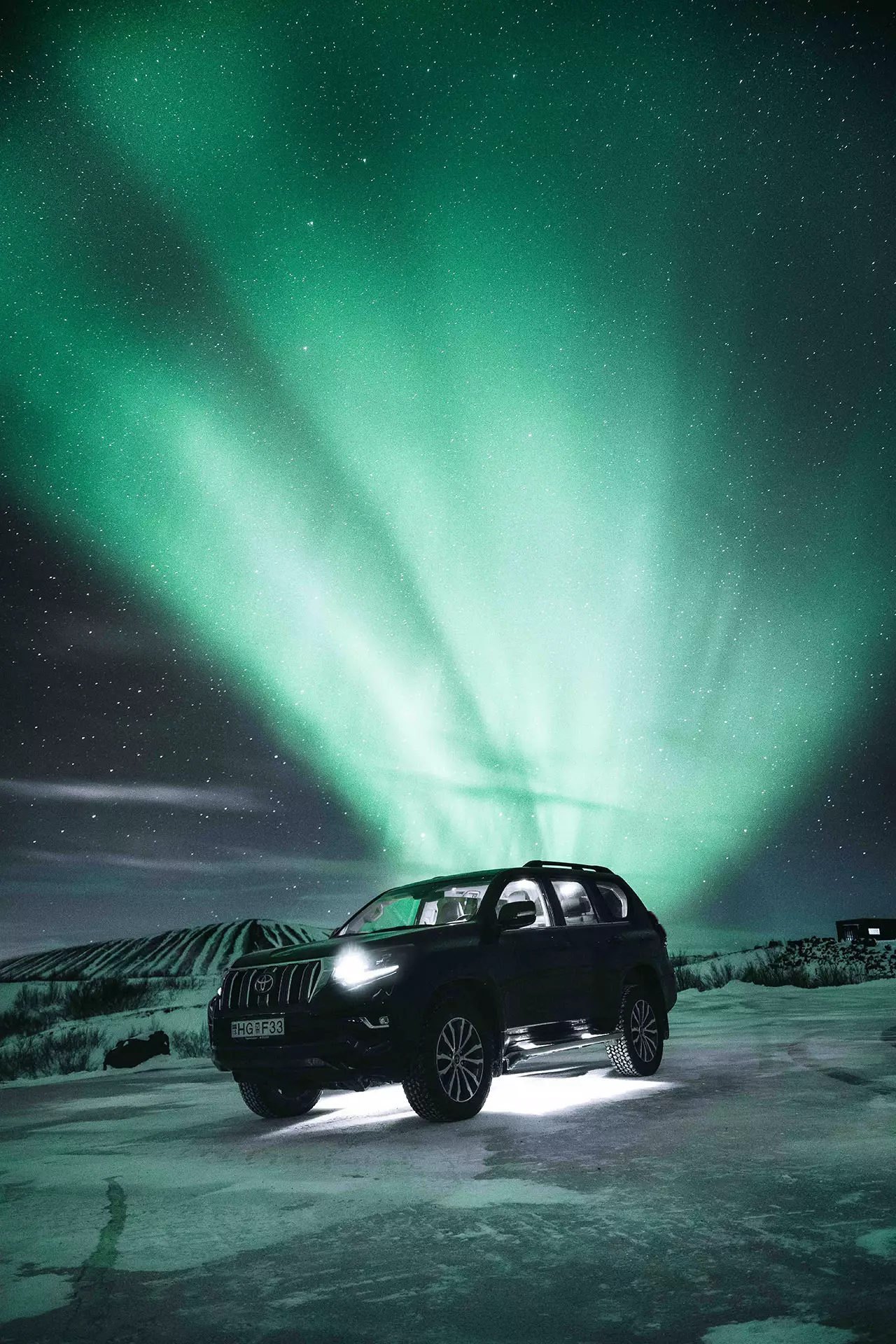 Coche de alquiler bajo la aurora boreal en Islandia.